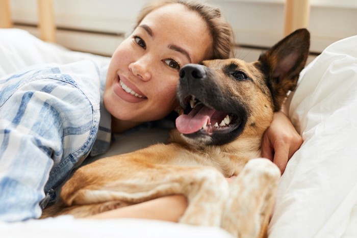 ベッドでくつろぐ女性と犬