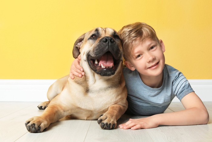 寄り添って床に寝そべる犬と男の子