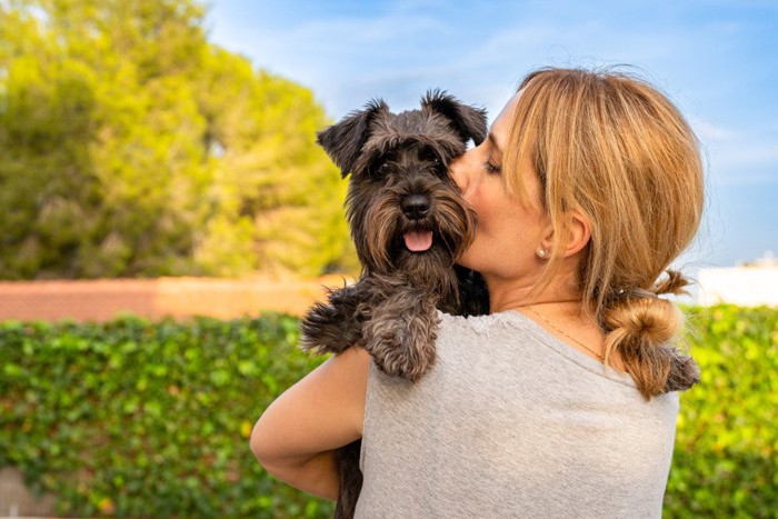 犬と顔をくっつけ合う女性