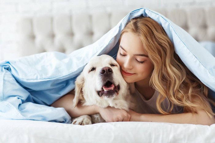 ベッドで犬をハグする女性