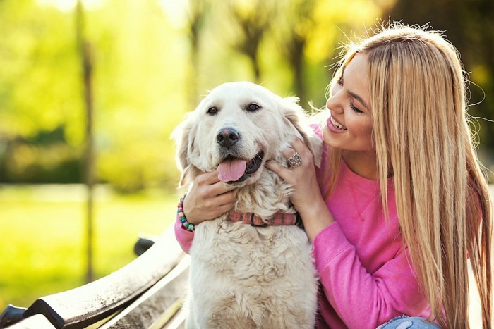 後ろから犬を撫でる笑顔の女性