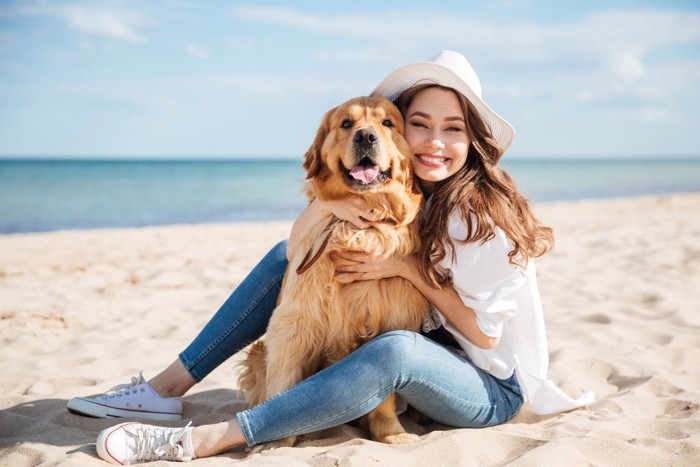 ビーチで触れ合う飼い主の女性と犬