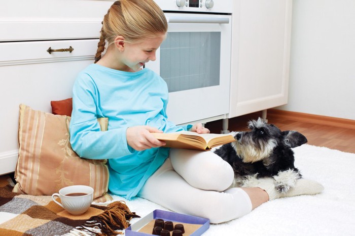 カーペットの上で寛ぐ女の子と犬