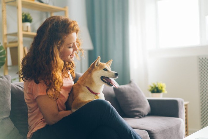 女性にお尻をくっつけて座る犬