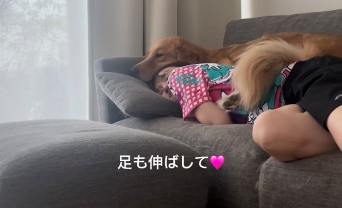 飼い主の体の上に足を伸ばす犬