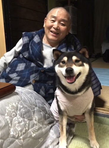 コタツのに座るおじいちゃん、笑顔で寄り添う黒柴
