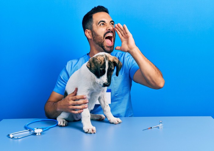 叫ぶ男性のそばでうなだれる犬