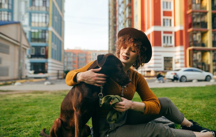 右手で犬の肩を抱いて座る女性