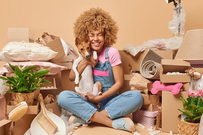 散らかった部屋で犬を抱っこする女性