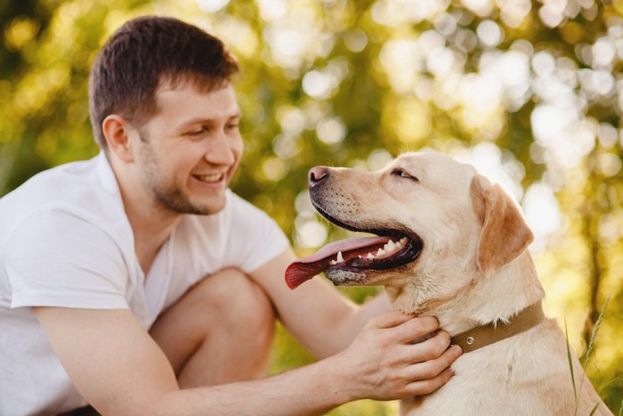 笑顔で見つめ合う男性と犬