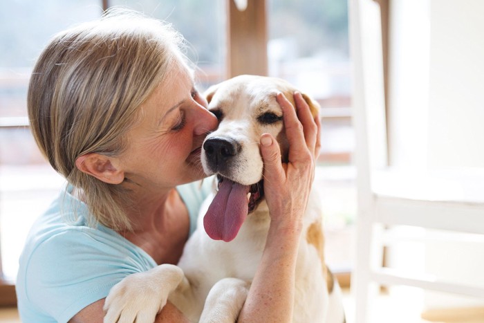 犬の頬に口元を寄せる女性