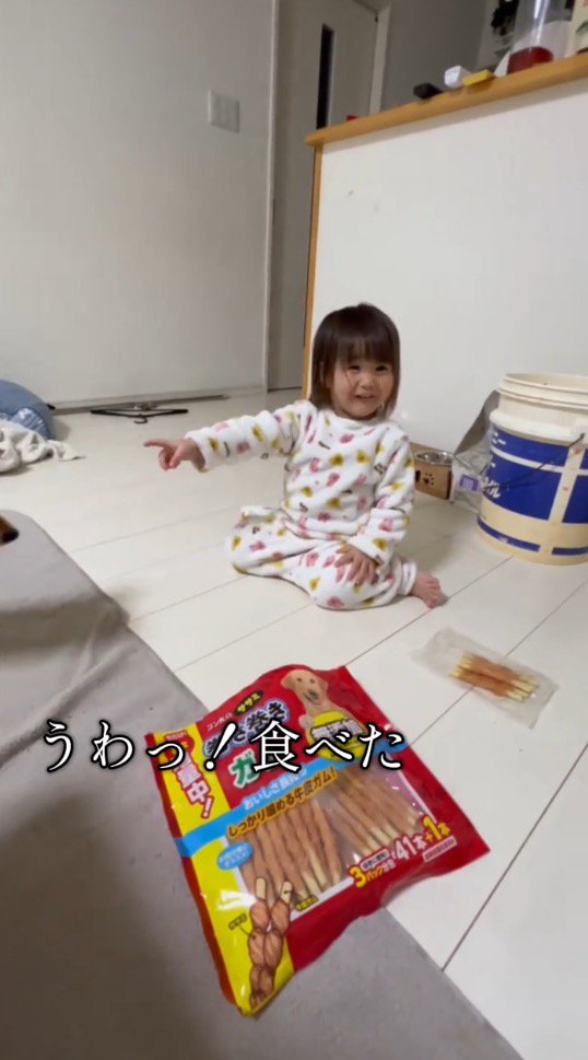 おやつを持っていた犬を見て笑顔になる女の子