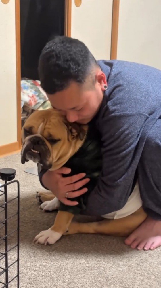 犬を背中側から抱きしめる男性