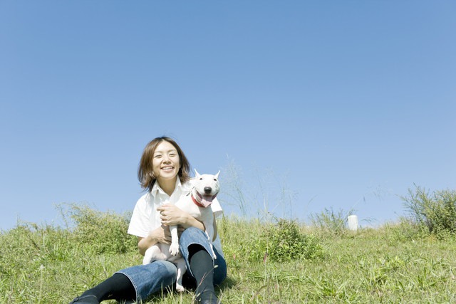 抱っこされて川原に座る犬