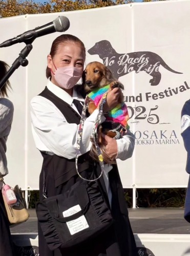 飼い主に抱っこされながらカメラを見つめる犬