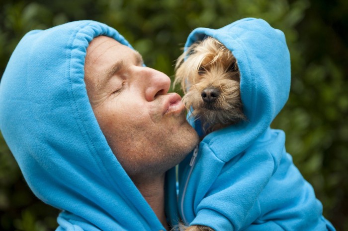 男性にキスされそうな犬