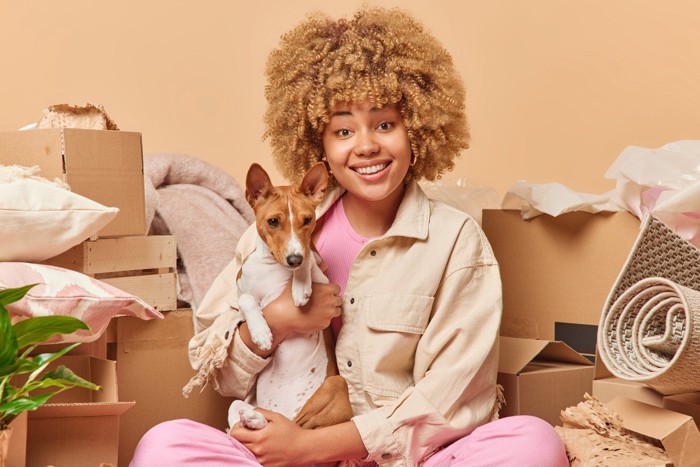 散らかる部屋にいる女性と犬