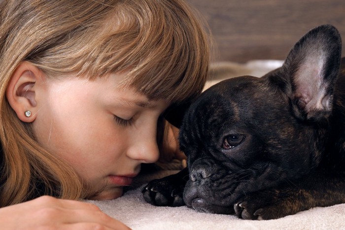 顔を寄せ合う女の子と犬