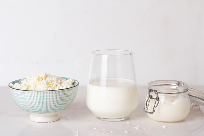 牛乳が入ったグラスの隣に置かれたヨーグルトとカッテージチーズ