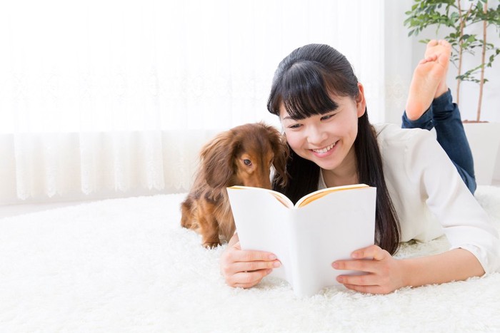 一緒に本を覗く犬と女性