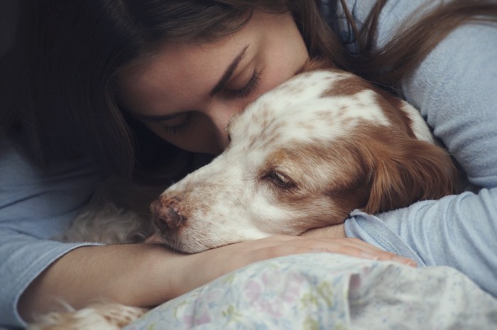 眠る犬を抱きしめる女性