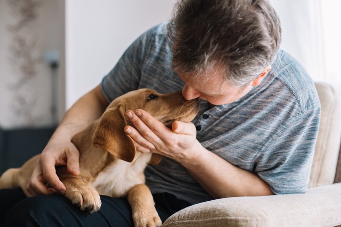 顔を寄せ合う男性と犬