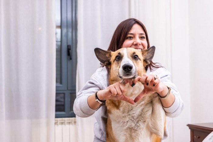 犬とハートマークを作る女性