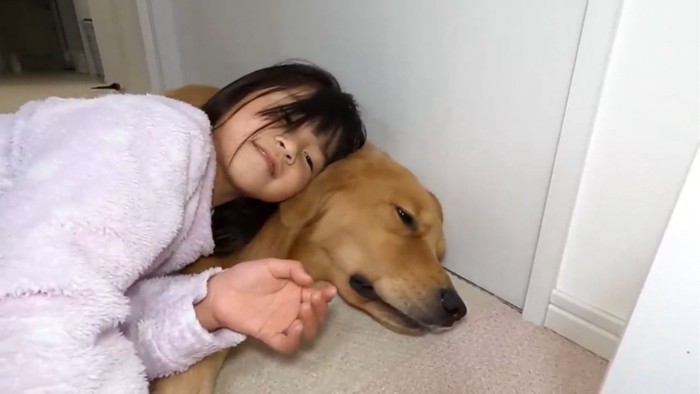 顔を寄せ合って横になる子供と犬