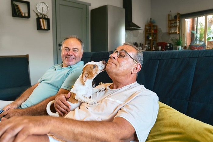 二人の男性と顔を舐める犬