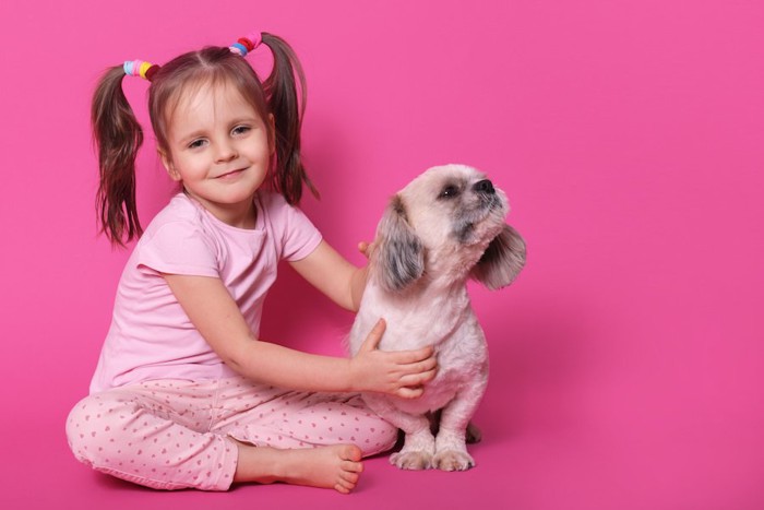 ピンクの服を着た少女とそっぽを向く犬