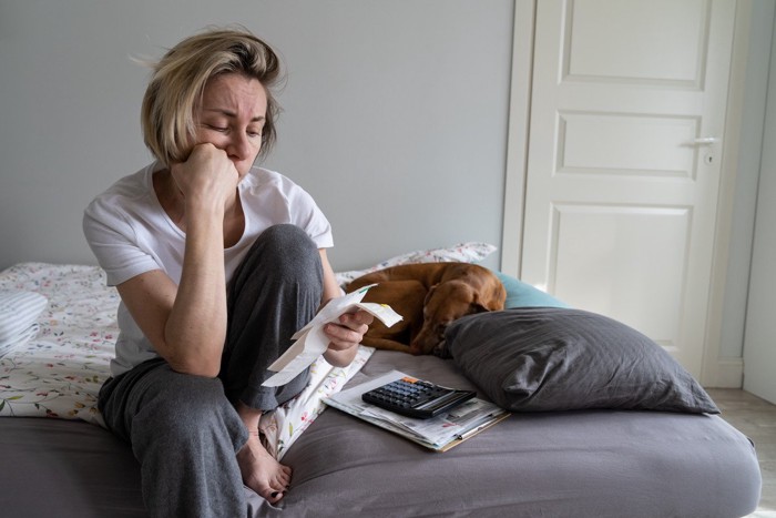 悩む女性の隣で眠る犬