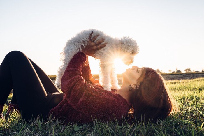 自分の上に愛犬を乗せる女性