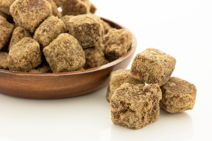 木の器とテーブルに置かれた塊状の黒糖