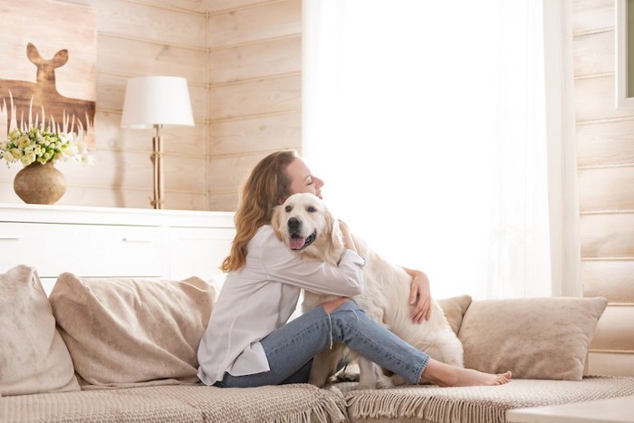 ソファーで犬を抱きしめる女性