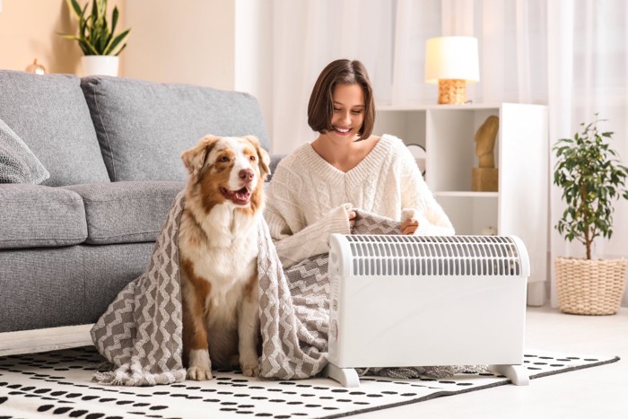 暖房の横に座る犬と女性