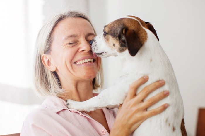 人の顔を舐める犬、抱えられている