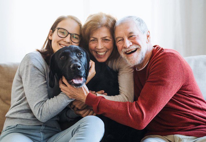 家族3人に囲まれる黒い犬