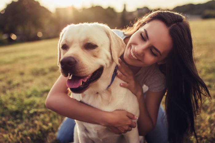 愛犬を後ろから抱きしめる女性