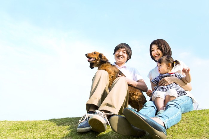 芝生でペットの犬と家族で楽しむ様子