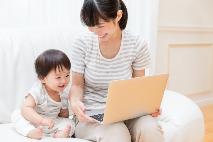 子どもと一緒にパソコンを見ている母親