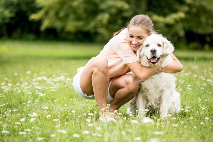 笑顔の女性に抱きしめられる犬