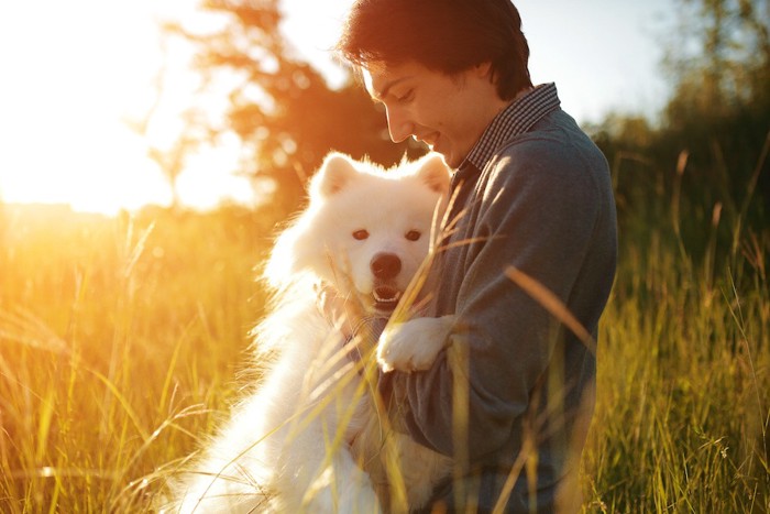 夕暮れに抱き合う人と犬