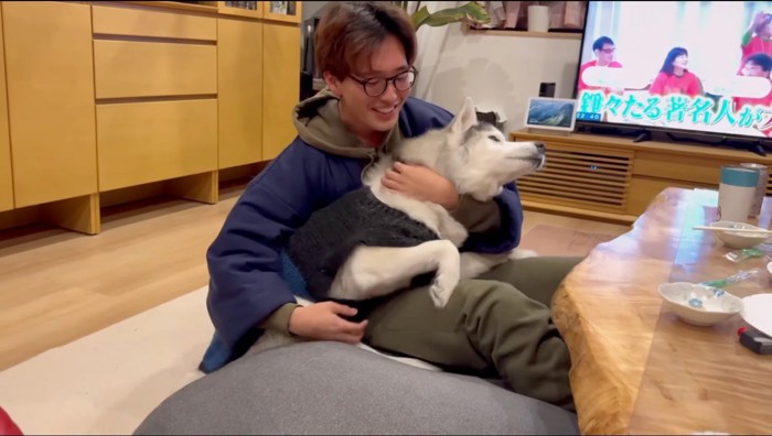 ハスキー犬を抱き抱えながら撫でる男性