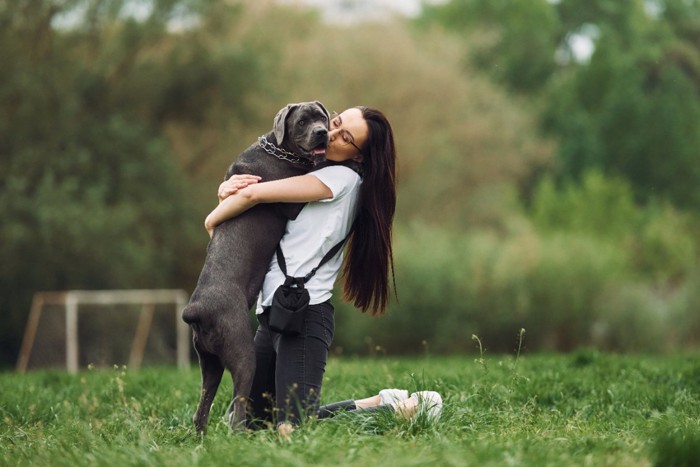 女性に抱かれている黒い犬