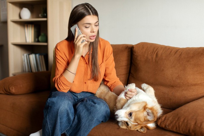 犬の足を見ながら電話する女性
