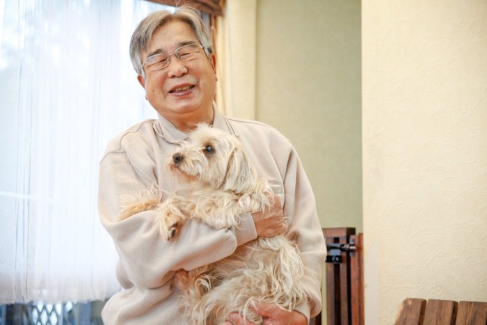 犬を抱く年配の男性