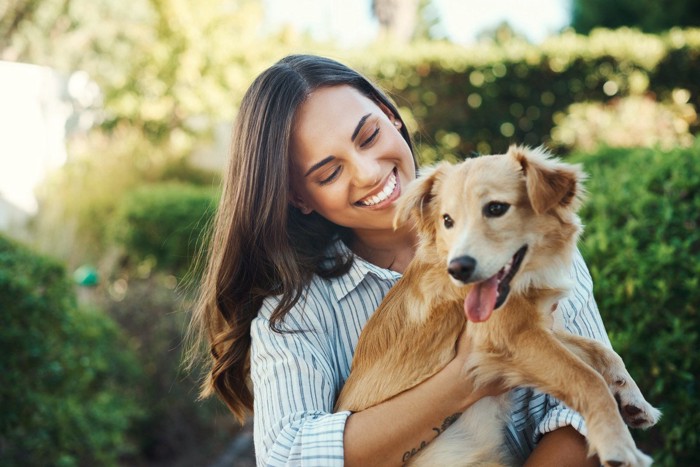 女性に抱っこされている犬