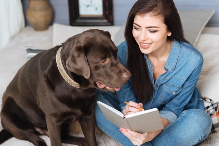 メモ帳をつける女性と犬