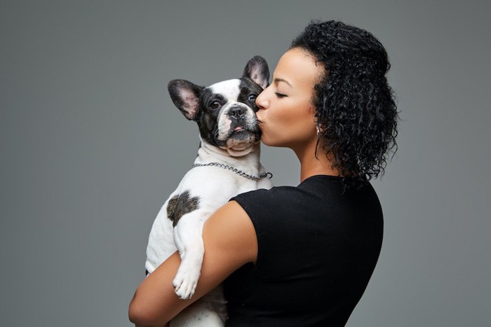 犬を抱き上げてキスをする女性