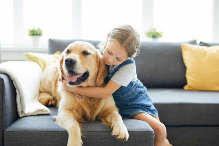 子どもに抱きしめられる犬